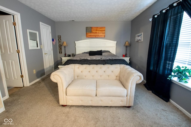 carpeted bedroom featuring a textured ceiling and baseboards