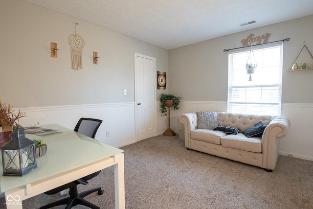 carpeted office space featuring visible vents and a textured ceiling