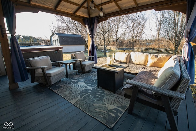 wooden deck featuring an outbuilding, a gazebo, fence, a shed, and an outdoor living space