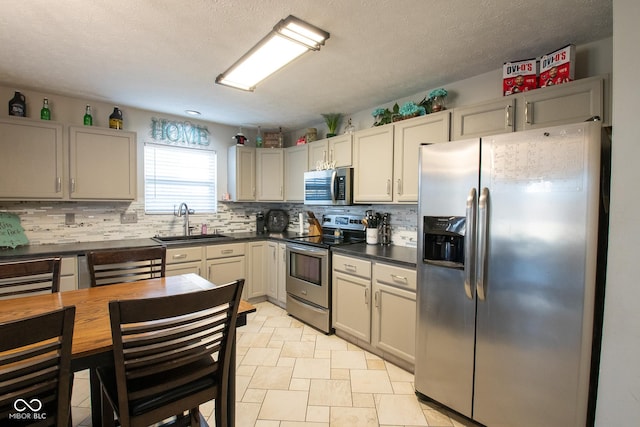 kitchen with dark countertops, tasteful backsplash, stainless steel appliances, and a sink