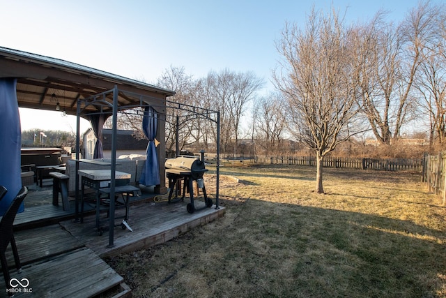 view of yard featuring a trampoline, a fenced backyard, a hot tub, and a wooden deck