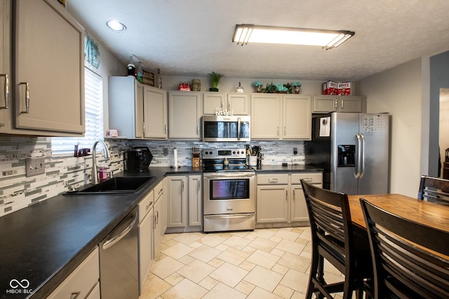 kitchen with dark countertops, tasteful backsplash, stainless steel appliances, and a sink