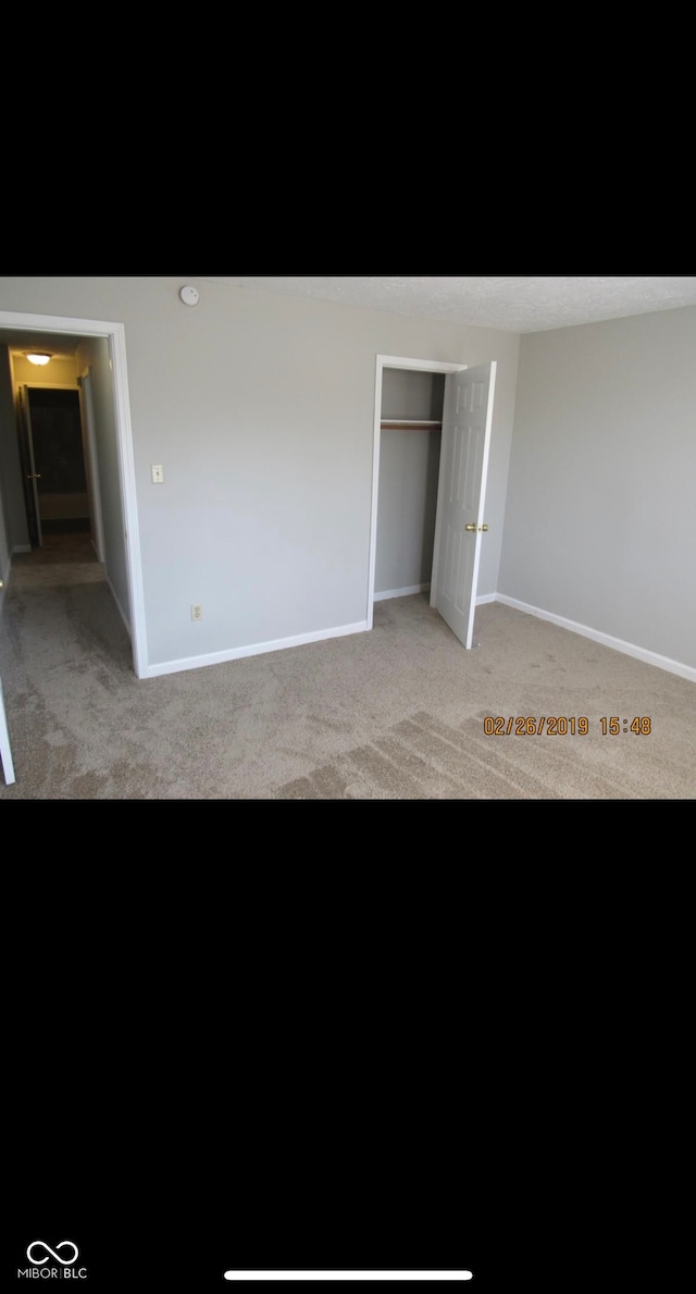 unfurnished bedroom featuring a closet, light carpet, and baseboards