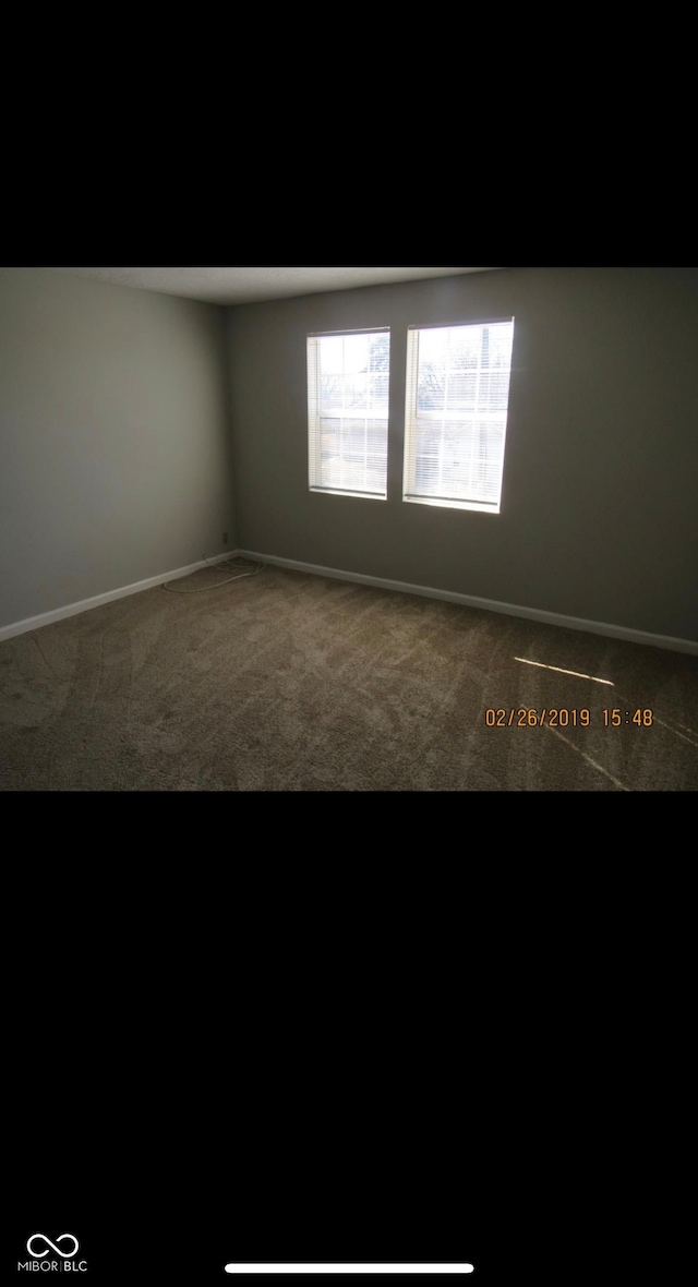 spare room featuring carpet flooring and baseboards