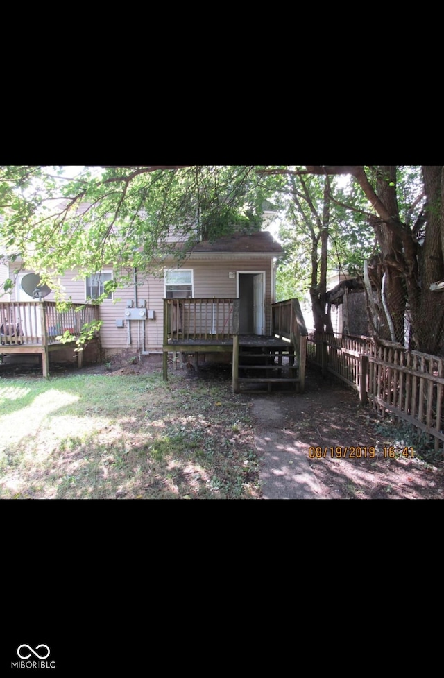 rear view of house with fence and a deck