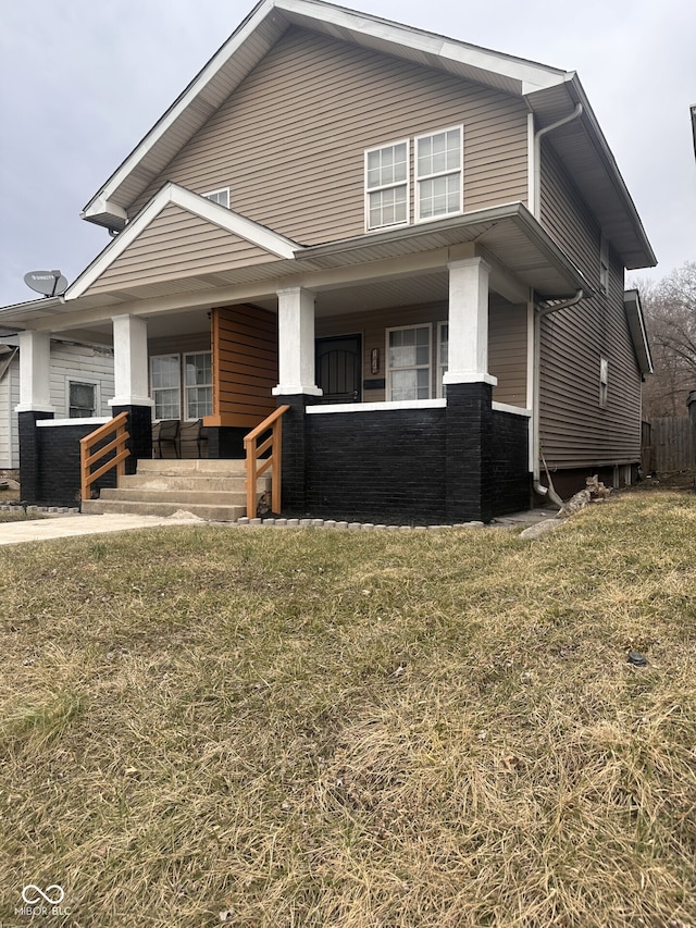 view of front of property with covered porch, a front lawn, and brick siding