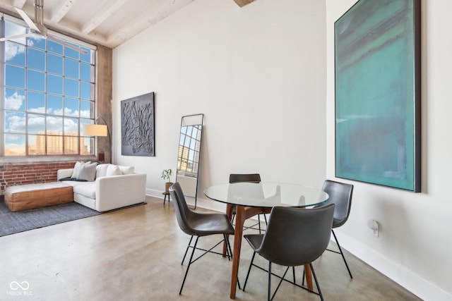 dining room with baseboards, concrete floors, and a towering ceiling