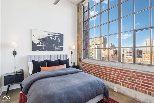 bedroom featuring a city view, a towering ceiling, and brick wall