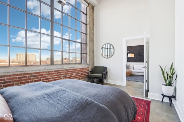 bedroom featuring multiple windows, baseboards, concrete floors, and a towering ceiling