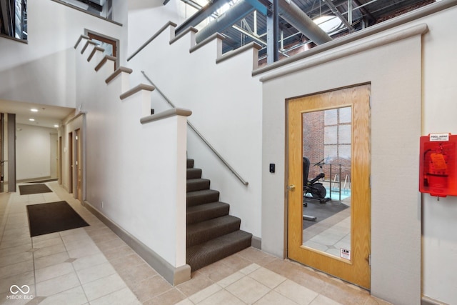 stairs with tile patterned floors and a towering ceiling