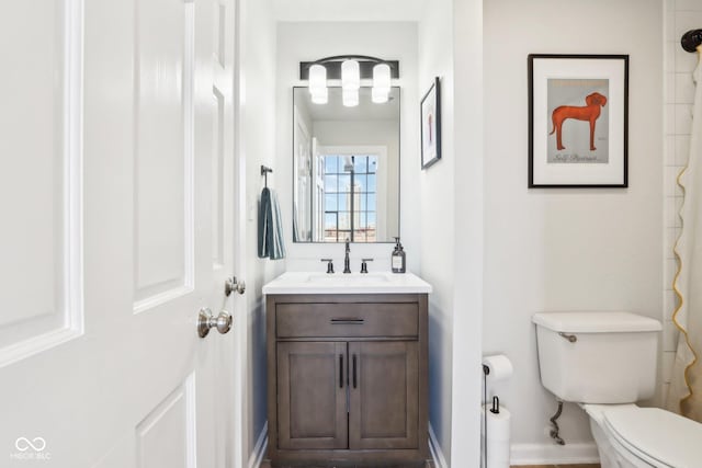 full bathroom featuring baseboards, toilet, and vanity