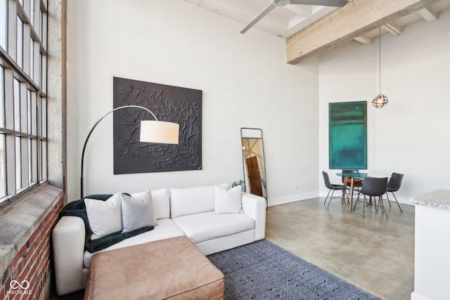 living room with concrete floors, ceiling fan, baseboards, beam ceiling, and a towering ceiling