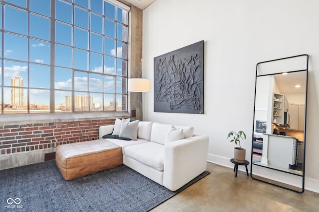 living area featuring baseboards, a high ceiling, a city view, and finished concrete floors