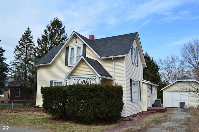 view of front facade featuring a garage, an outdoor structure, a chimney, and fence