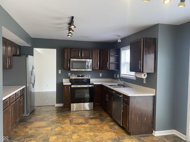 kitchen with dark brown cabinets, stainless steel appliances, a sink, and light countertops