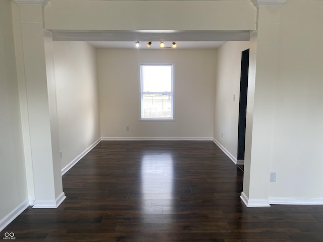 spare room featuring dark wood-style flooring and baseboards