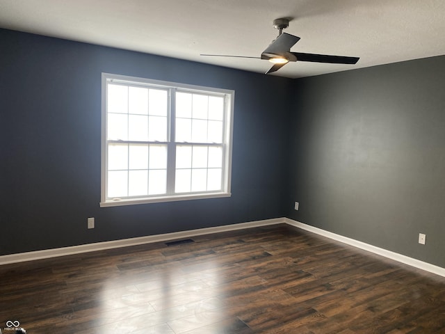 unfurnished room featuring a ceiling fan, visible vents, dark wood finished floors, and baseboards