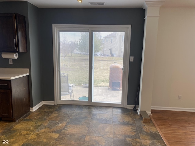 entryway featuring visible vents, stone finish flooring, decorative columns, and baseboards