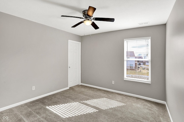 carpeted spare room with a ceiling fan, visible vents, and baseboards