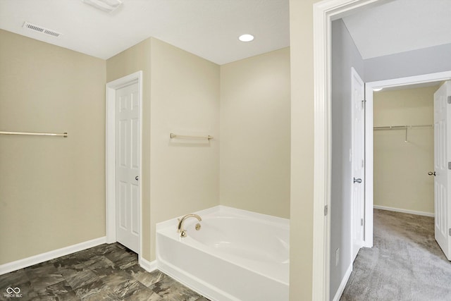 full bath featuring a garden tub, baseboards, a spacious closet, and visible vents