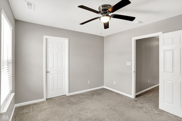 unfurnished bedroom featuring carpet, visible vents, baseboards, and a ceiling fan