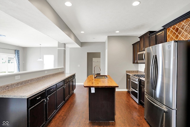 kitchen with butcher block countertops, appliances with stainless steel finishes, dark wood-style flooring, and a sink