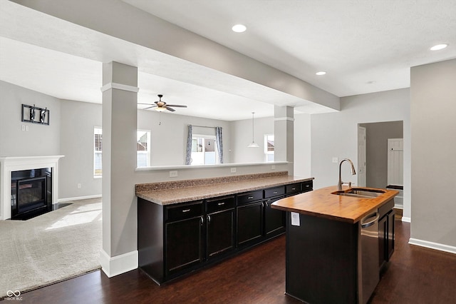 kitchen featuring dark cabinets, butcher block counters, a sink, and open floor plan