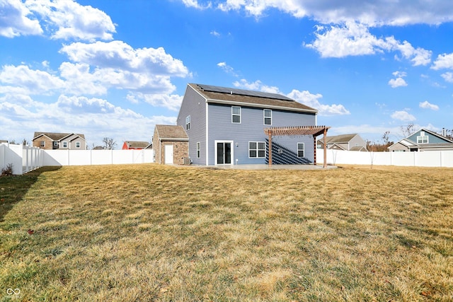 back of property featuring a fenced backyard, a lawn, a pergola, and solar panels