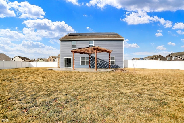 rear view of property with roof mounted solar panels, a lawn, a pergola, and a patio