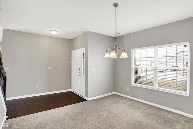 interior space featuring baseboards, a chandelier, and dark colored carpet