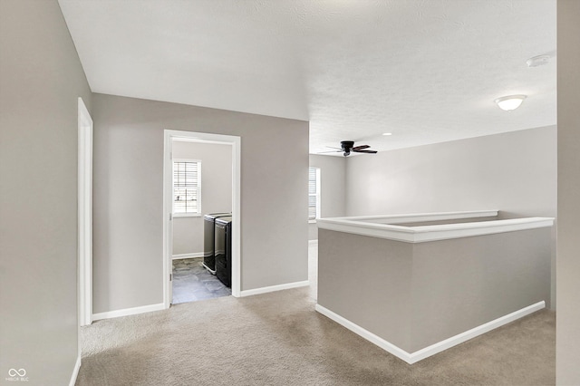 corridor with washer and clothes dryer, carpet flooring, a textured ceiling, an upstairs landing, and baseboards