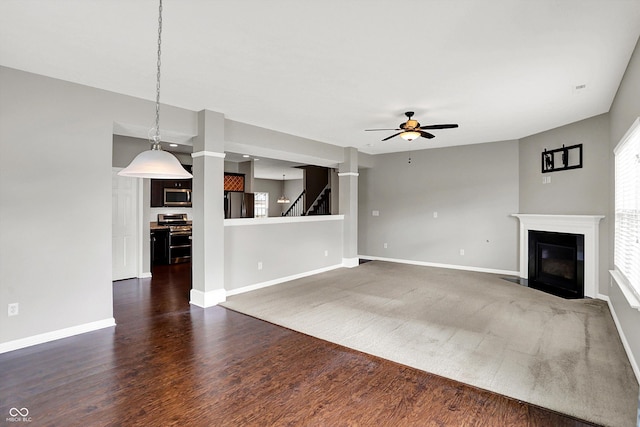 unfurnished living room with baseboards, a ceiling fan, a fireplace with flush hearth, stairway, and dark wood-style flooring