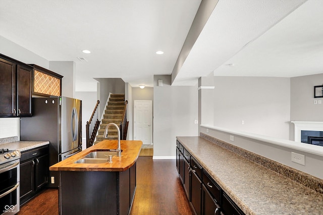 kitchen with stainless steel appliances, dark wood finished floors, butcher block counters, and a sink