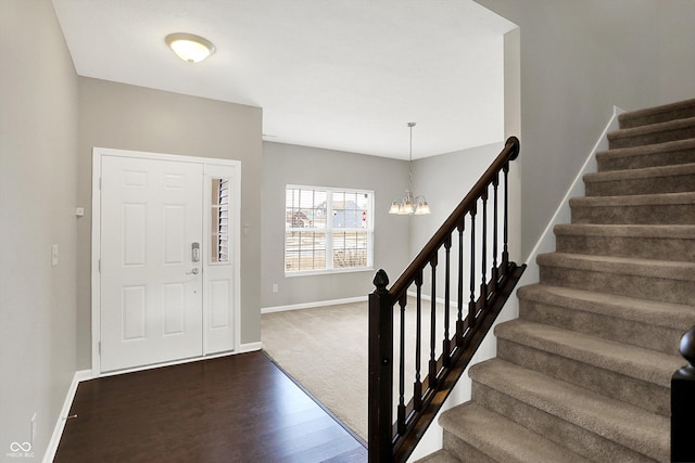 entryway featuring a notable chandelier, stairway, dark wood finished floors, and baseboards