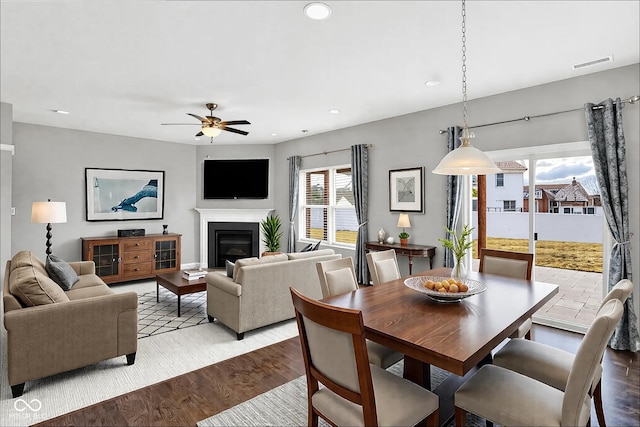 dining room featuring recessed lighting, visible vents, a ceiling fan, a glass covered fireplace, and wood finished floors