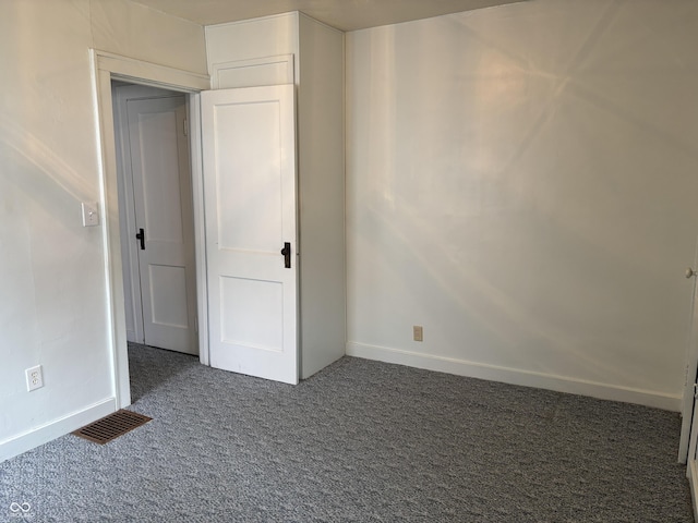 unfurnished bedroom featuring baseboards, visible vents, and dark colored carpet