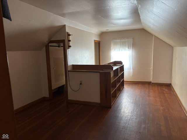 additional living space featuring lofted ceiling, baseboards, and dark wood-type flooring