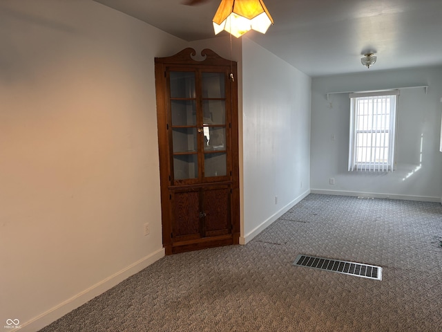 carpeted spare room featuring visible vents and baseboards