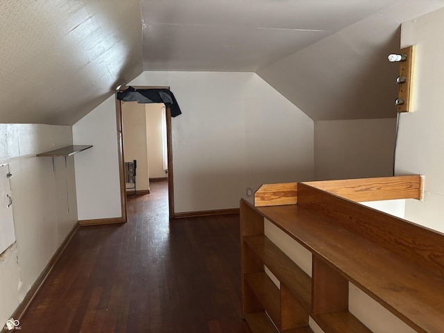 bonus room featuring lofted ceiling, dark wood-style flooring, and baseboards