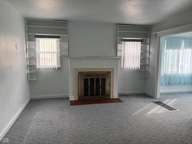 unfurnished living room with a fireplace with flush hearth, carpet flooring, visible vents, and baseboards