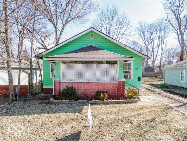 bungalow with a shingled roof and brick siding