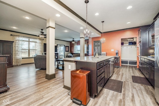 kitchen featuring ceiling fan, ornamental molding, open floor plan, light wood-style floors, and a sink