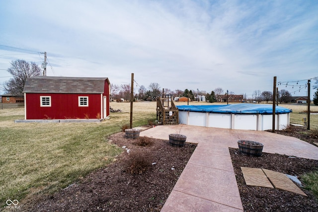 view of pool featuring an outbuilding, a covered pool, a lawn, and a storage unit