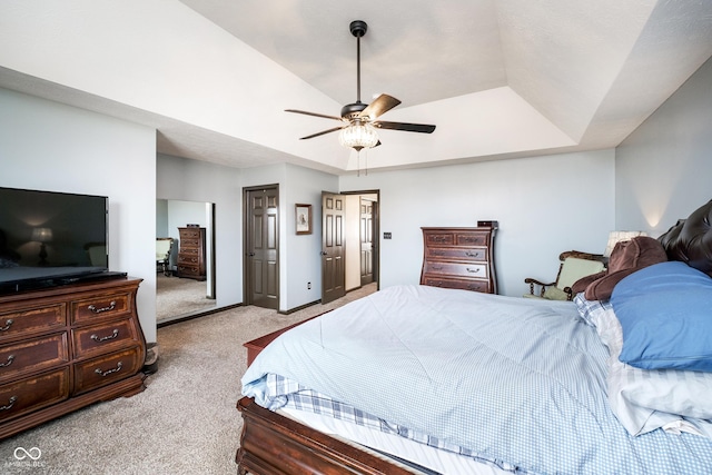 carpeted bedroom with ceiling fan, a raised ceiling, and baseboards