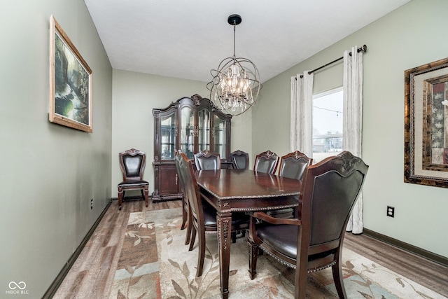 dining room featuring a notable chandelier, baseboards, and light wood-style floors