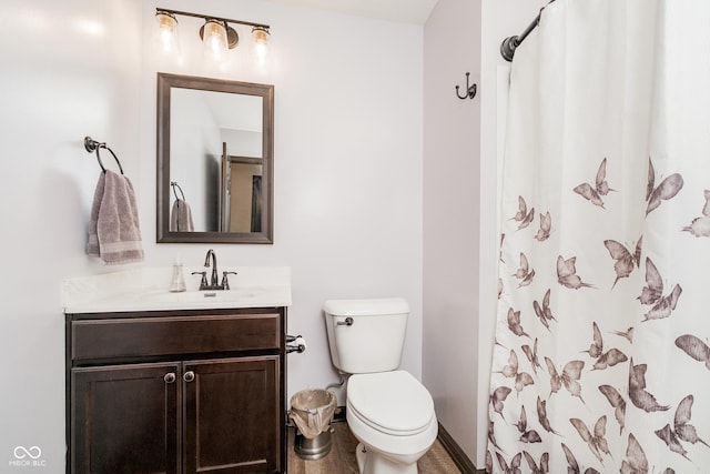 bathroom featuring curtained shower, baseboards, vanity, and toilet