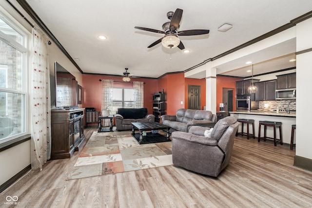 living area with light wood-style flooring, recessed lighting, baseboards, ornamental molding, and ornate columns