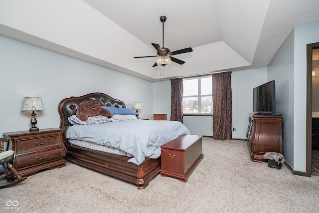 carpeted bedroom with ensuite bath, ceiling fan, baseboards, and a raised ceiling