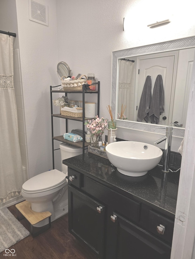 full bathroom featuring visible vents, a shower with shower curtain, toilet, vanity, and wood finished floors