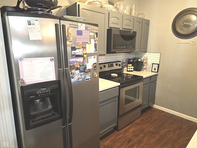 kitchen with dark wood finished floors, stainless steel appliances, gray cabinets, light countertops, and backsplash